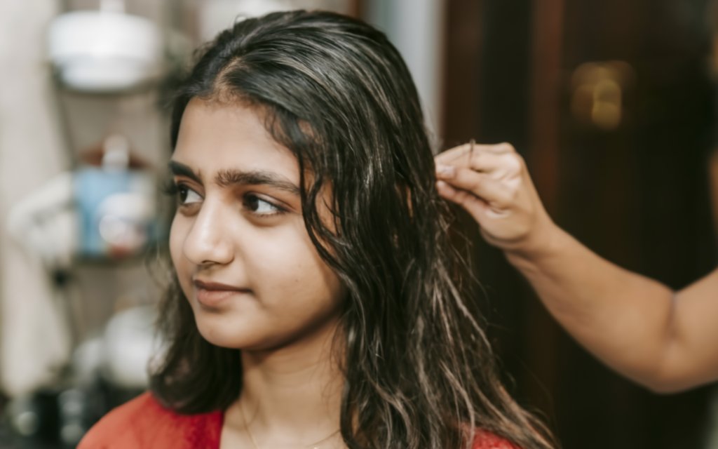 Girl smoothening her hair by professional hair stylist at home